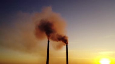 Gün batımında borulardan portakal dumanı çıkıyor. Gökyüzü arka planında havada kirli emisyonlar var. Ekoloji kirliliği.