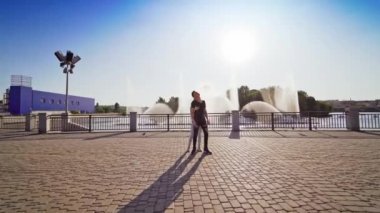 Sokak dansı. Dışarıdaki fıskiyenin arka planında iki profesyonel dansçı var. Siyahlı çocuk ve beyazlı kız serbest dans ediyor..