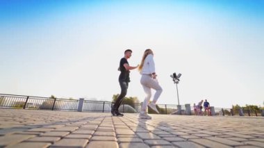 Genç dansçılar birlikte hareket ediyorlar. Dans eden çift sokakta serbest dans gösterisi sergiliyor. Asfaltta dans eden şık erkek ve kadın.