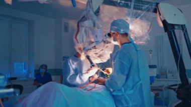 Operasyon süreci. Mavi üniformalı doktorlar hastanenin modern ameliyathanesinde ameliyat yapıyorlar..