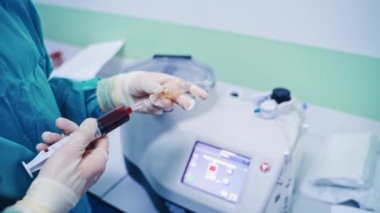 Kök hücre enjeksiyon prosedürü. Kadın işçi şırıngadan özel makineye kan döker. Klinikte modern ekipman.