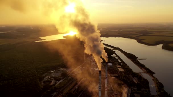 日没時に自然エネルギー工場 夕方の川の背景にある工業用パイプから出てくる濃い煙 大気汚染だ 空中風景 — ストック動画