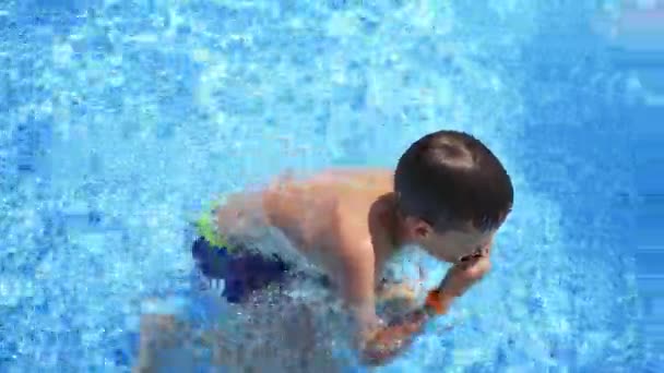 Chlapec plavající v bazénu. Teenager plave pod vodou v bazénu. Dítě se baví v aquaparku za slunečného dne.