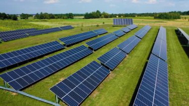 Güneş panellerinin üst görüntüsü, yeşil çimen ve güneş ışığıyla alternatif enerji çiftliğindeki güneş hücresi yansıyor. Fotovoltaik bitki alanı. Çevre enerjisi.