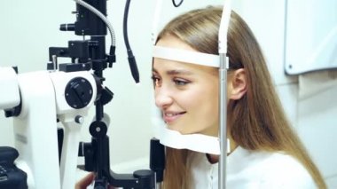 Klinikte gözlerini kontrol eden genç bir kadın. Biyomikroskopi cihazı. Modern tıbbi ekipmanların yardımıyla bir kadın hastanın göz yapısını inceleyen bir doktor. Profesyonel sağlık hizmetleri.