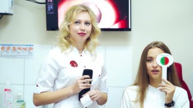 Doktor ve hasta görüşü kontrol ediyor. Bir gözü kapalı, görüş testi yapan bir kadının ön görüntüsü. Oftalmoloji kabinesi.