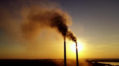 Fabrikadan gelen kara duman. Endüstriyel üretim boruları gün batımında atmosferi kirletir. Havada zehirli duman var. Ekolojik sorunlar.