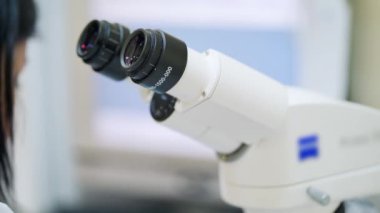 Modern mikroskopta bir kadın. Laboratuvarda mikroskop var. Tıbbi asistan çağdaş cihaza bakıyor. Tıpta yeni teknolojiler.