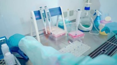 Test tüpleriyle laboratuvar çalışanı. Modern bir laboratuvar. Steril eldiven asistanı araştırma laboratuarında şişeyi sıvıyla dolduruyor..