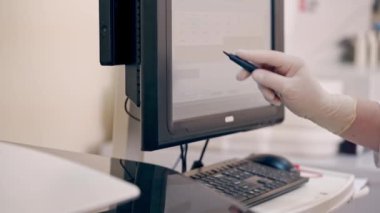 Laboratuvar çalışanı modern cihaz kullanıyor. Özel kalem tutan bir tıp asistanı ve klinikteki bir monitör üzerinde çalışıyor. Laboratuvarda çağdaş ekipmanlar.