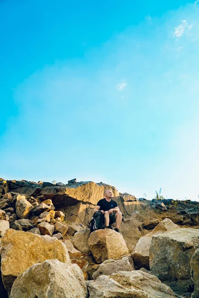 Dinlenmiş Genç Bir Turist Kayanın Arka Planında Oturuyor Önüne Bakıyor — Stok fotoğraf