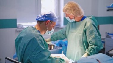 Cerrah ve asistan ameliyat yapıyor. Modern bir ameliyathanede koruyucu giysi konusunda uzman bir erkek. Hemşire asistanı..
