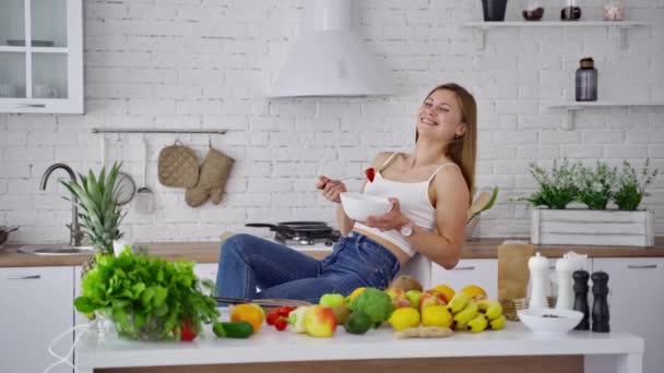 微笑的女人吃着健康的食物 美丽的年轻女士坐在厨房里 吃着新鲜有机食品背景下的沙拉 — 图库视频影像