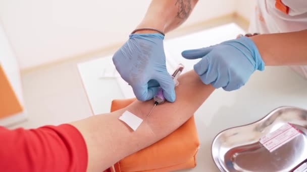 静脈から血液サンプルを採取するプロセス 青い手袋の看護師の手は患者の静脈に針を刺す 静脈から血液を採取する医療助手 — ストック動画