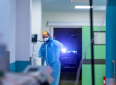 Covid 19, Coronavirus hastaneleri. Korunaklı maske ve eldivenli doktor koronavirüs ve salgın sırasında telefonla konuşuyor. Doktor çalışıyor ve hastane binasında arama yapıyor. Boşluğu kopyala.