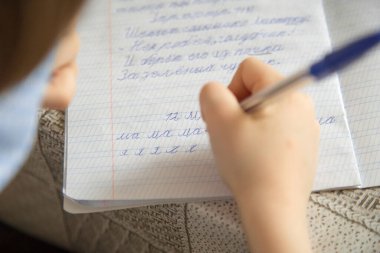 Maskeli bir çocuk koronavirüs yüzünden karantinada ödev yapıyor..