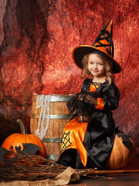 Frohes Halloween! fröhliches kleines Mädchen im Hexenkostüm sitzend lizenzfreie Stockfotos