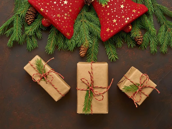 Composición navideña de campanas rojas, ramas de abeto, regalos en kraft — Foto de Stock