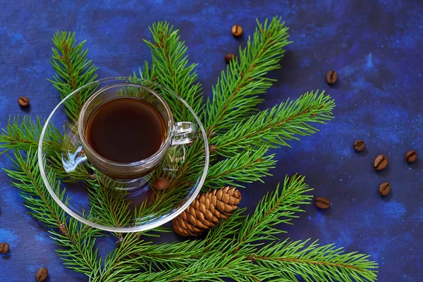 Filiżankę kawy na talerzyk i jodła gałęzie drzew na niebiesko — Zdjęcie stockowe