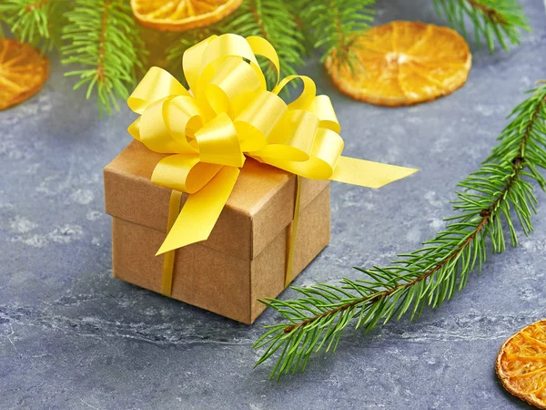 Caixa de presente Natal Kraft com arco amarelo em um backgro de pedra cinza Fotos De Bancos De Imagens