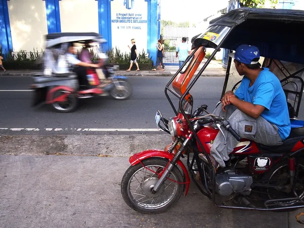 Motorista triciclo pacientemente espera em uma calçada para os passageiros — Fotografia de Stock