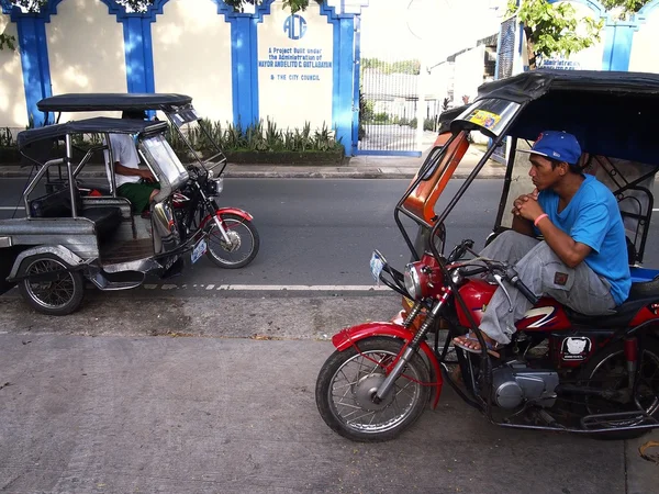 Motorista triciclo pacientemente espera em uma calçada para os passageiros — Fotografia de Stock