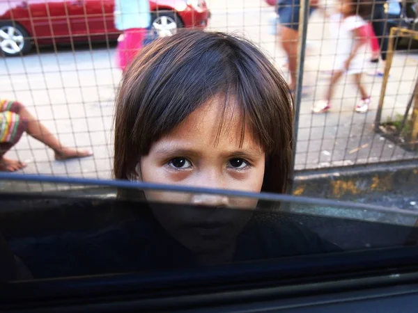 A child looks into a car window asking for some money. — Stock Photo, Image