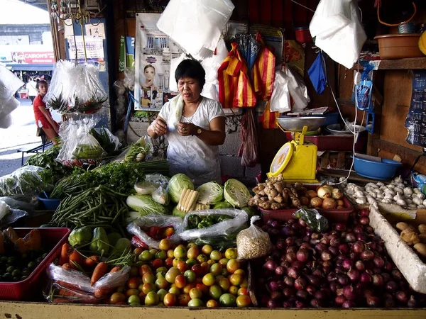 Un vendedor de mercado dentro de un puesto de frutas y verduras en un mercado público . — Foto de Stock