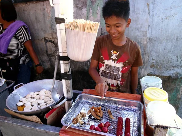 Un vendedor ambulante de comida cocina bocadillos en su carrito de comida . — Foto de Stock