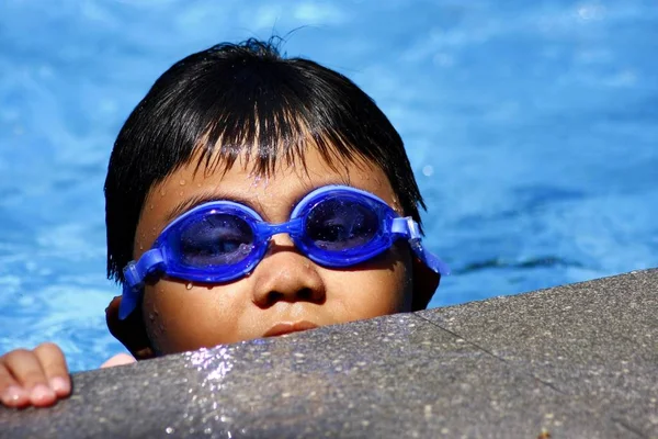 Jeune enfant avec des lunettes de natation dans une piscine . — Photo