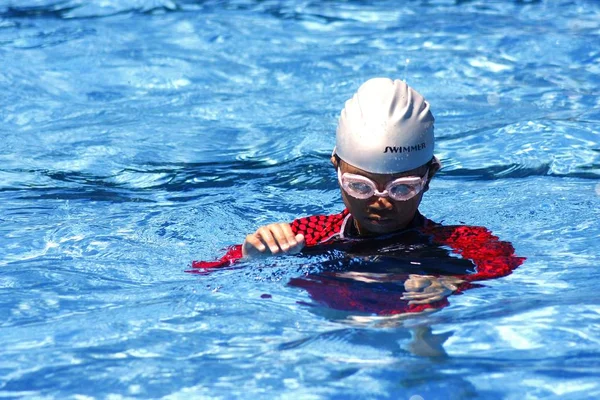 Um garoto com óculos de proteção em uma piscina . — Fotografia de Stock