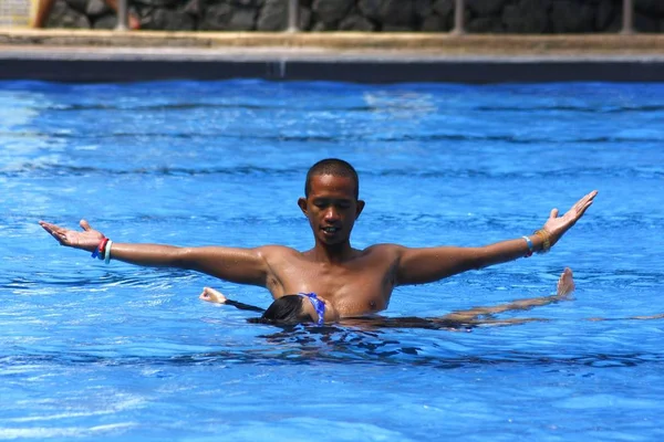 Un entraîneur de natation apprend à un jeune enfant comment flotter sur le dos dans une piscine . — Photo