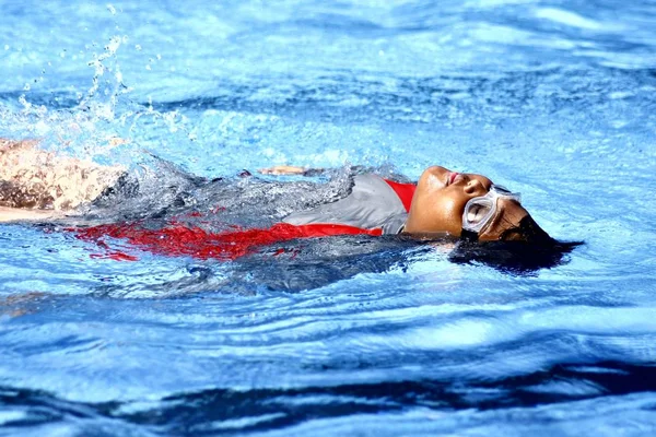 Genç bir çocuğun öğrenir nasıl sırtında bir yüzme havuzunda yüzen. — Stok fotoğraf