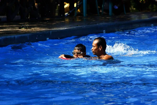 Un niño aprende a nadar con la ayuda de un entrenador de natación . —  Fotos de Stock