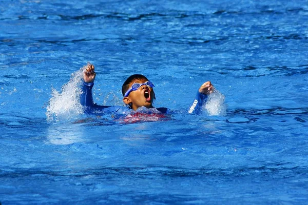 Un niño jadea por aire mientras aprende a hacer el golpe de pecho en un entrenador de natación . —  Fotos de Stock