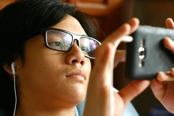 Adolescente con anteojos usando un teléfono inteligente — Foto de Stock