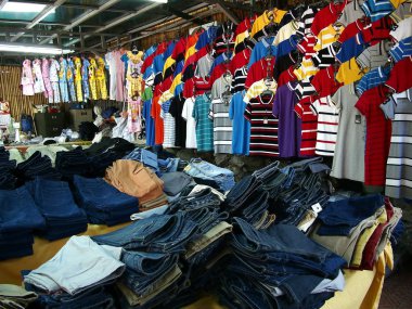 Çeşitli renkli gömlek ve pantolon veya pantolon bir giysi dükkanında satışa.