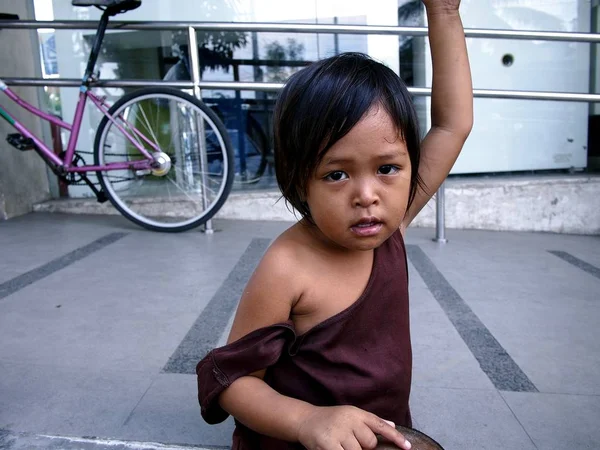 Une jeune fille se repose sur un trottoir et regarde la caméra . — Photo