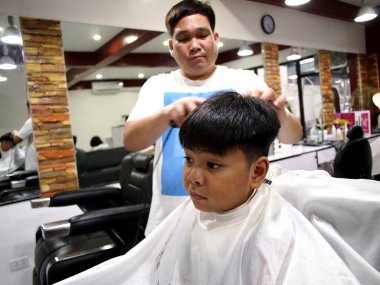 Genç bir çocuk bir saç kesimi bir kuaför dükkanında alır..