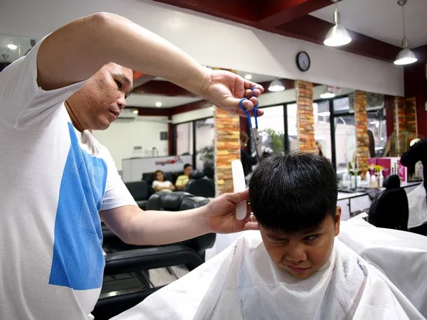 Genç bir çocuk bir saç kesimi bir kuaför dükkanında alır..