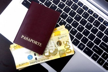 Pasaport ve Filipin Pezosu faturaları bir dizüstü bilgisayar üzerinde.