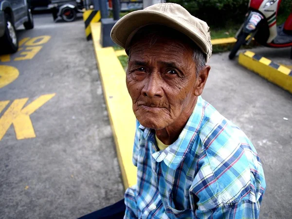 Starszy człowiek patrzy w kamerę podczas odpoczynku na chodniku. — Zdjęcie stockowe