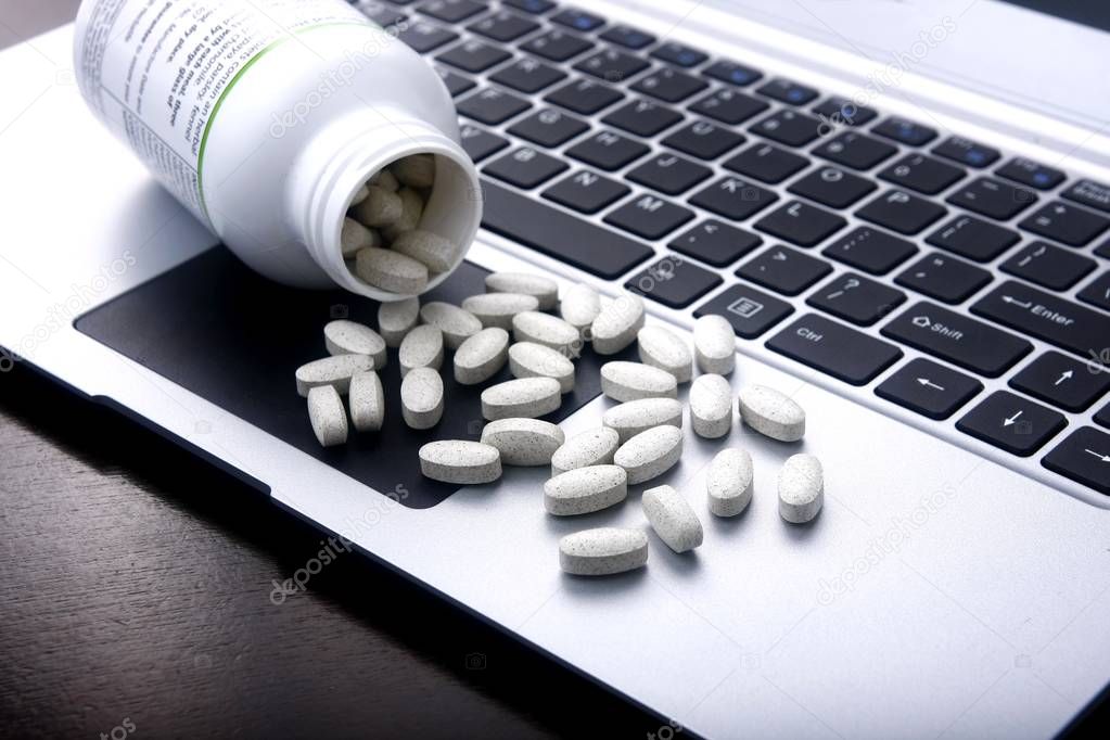 Medicine tablets on a laptop computer.