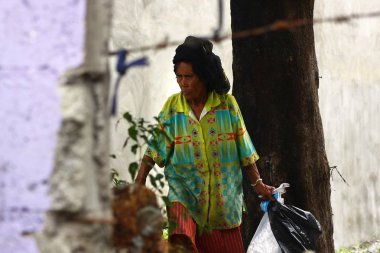 Yaşlı bir kadın AVI veya terk edilmiş bir çok çöp yığını geri dönüşümlü malzemeler için scavenges.