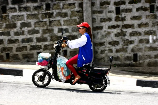 女性に乗る彼女の電子自転車や電動スクーター アンティポロで上り坂の道. — ストック写真