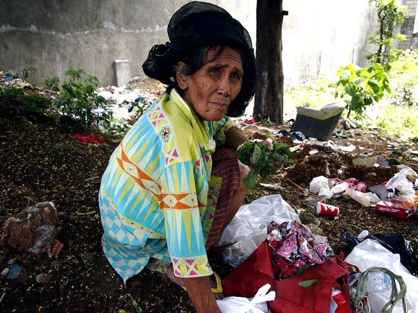 Стара леді полює або scavenges для вторсировини в купу сміття в занедбані багато. — стокове фото