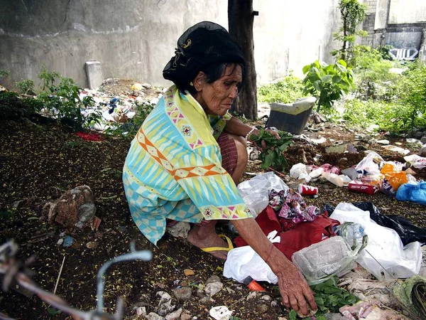 Стара леді полює або scavenges для вторсировини в купу сміття в занедбані багато. — стокове фото