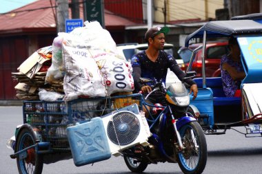 Bir adam bir üç tekerlekli bisiklet üzerinde geri dönüşümlü malzeme taşıma.
