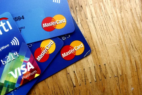 Un montón de tarjetas de crédito Mastercard y Visa repartidas en una mesa de madera — Foto de Stock