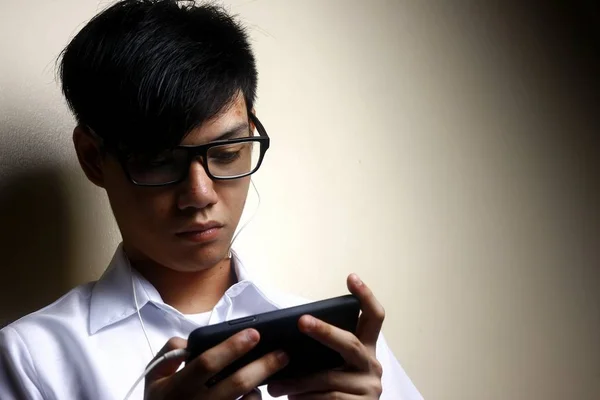 Teen using a smartphone with an earphone — Stock Photo, Image
